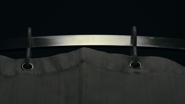 Dark hotel room shot of shower curtain moving on a rail