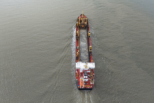 Aerial view of a trailing suction hopper dredger ship navigating through calm waters in the United Kingdom.