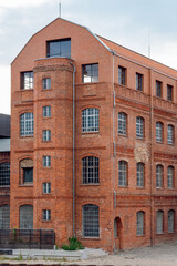 Restored red-brick facade, arched industrial windows, and distinctive turret tower of a historic industrial heritage building under an overcast sky in Berlin, Germany.    © Plamen Petrov