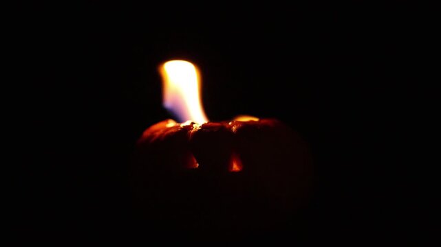 One-minute real-time 60fps video of a flaming Halloween pumpkin with glowing eyes and dancing flames on a black background.