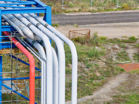 Aerial view of industrial pipes painted in red and grey, supported by a blue metal frame structure in an outdoor facility in the United Kingdom.