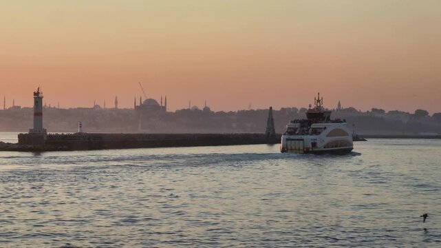 Ferry travels through the water at sunset with city skyline in the background