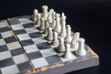 A chessboard with white pieces against a black background, a game that relies on strategy and intellectual acuity. © Randa