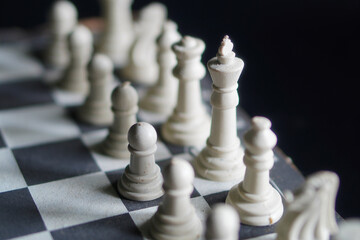 Close up, A chessboard with white pieces against a black background, a game that relies on strategy and intellectual acuity. © Randa
