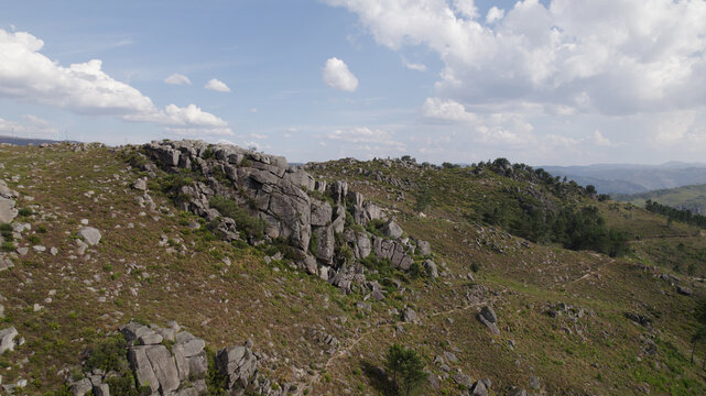 Aerial view of the rocky landscape of Peneda-Geres National Park with rugged granite outcrops, sparse shrubs, and rolling hills under a bright sky in Portugal.