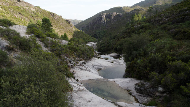 Aerial view of the rocky pools of Pocos Verdes Sete Lagoas nestled within the lush green hills and mountain landscape of Cabril, Vila Real, Portugal.
