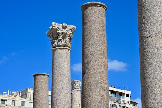 Low Angle Ancient Colonnade Detail with One Corinthian Order Capital and Modern Buildings in Lower Background