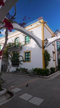 Vertical view of beautiful buildings and bougainvillea flowers in picturesque fishing old village Puerto de Mogan, Gran Canaria, Canary Islands, Spain