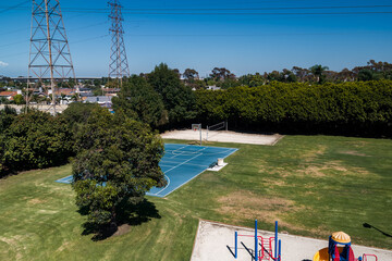 Aerial shot reveals a public community park complete with outdoor basketball court, volleyball sand...