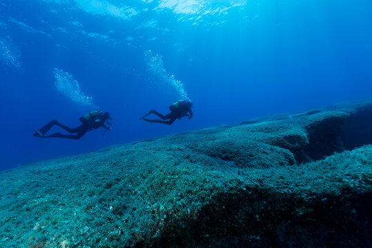 Two divers explore the rocky seabed