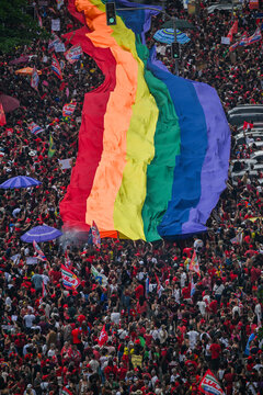 Rio de Janeiro, Brazil - 12 October 2026: Aerial view of a large crowd at a political rally, featuring a massive rainbow flag held aloft above the supporters.