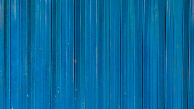 Bright blue corrugated metal shutter door texture with vertical lines background. Clean industrial rolling garage surface for architectural background and store front facade.