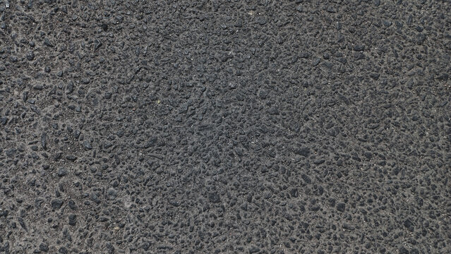 Close-up texture of dark black asphalt road pavement, rough mineral stone background for urban transportation backdrop.