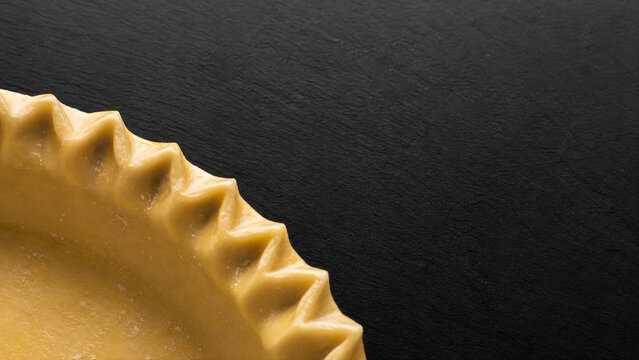 Crimped pie crust edge macro on black slate with egg wash glaze