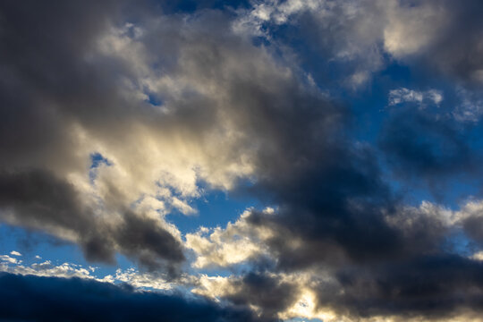 Dramatic clouds catching warm daylight across a blue sky