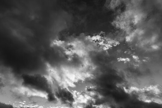 Monotone dramatic clouds catching sunlight across a stormy sky