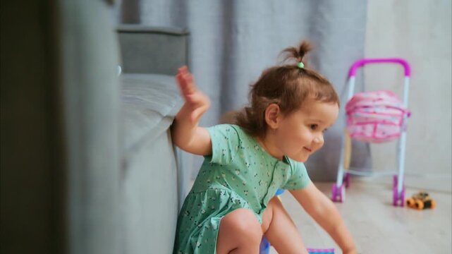 Little girl laughs, barefoot, in green dress. Pigtails bounce as she plays with toys nearby. Soft light glows behind her, gentle and warm. She beams, joyful, with bright, curious eyes