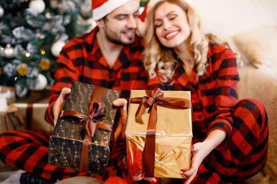 Couple wearing christmas plaid red pajamas sitting on the floor