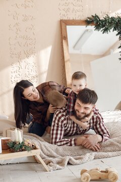 Young family in plaid shirts laying on a blanket and hugging
