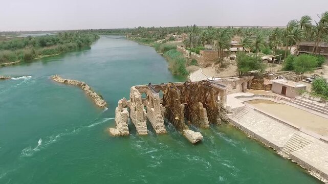 Slow drone orbit of the old norias and stone weir on the Euphrates River in Hit, Iraq