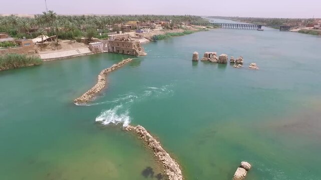 Drone gliding over the ancient stone weir and noria ruins in the Euphrates at Hit, Iraq