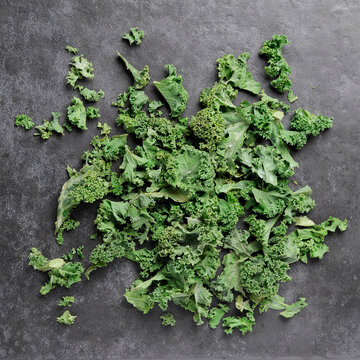 Chopped kale flat lay scattered on dark grey tile background