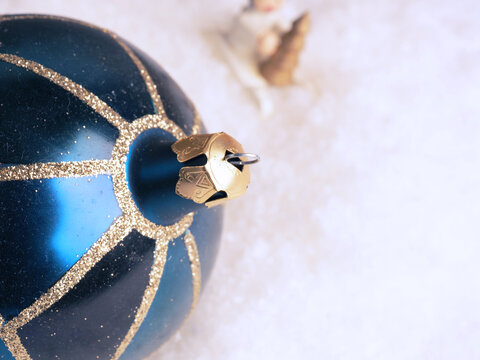 Wooden angel with blue Christmas bauble in snow