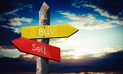 Buy or sell - wooden signpost with two arrows, sunset sky in background © PX Media
