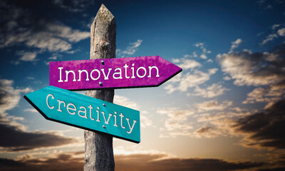 Innovation and creativity - wooden signpost with two arrows, sunset sky in background © PX Media