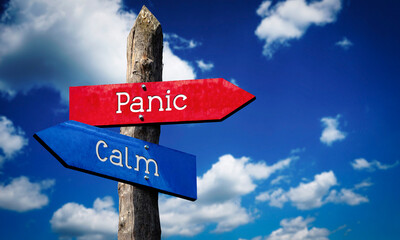 Panic or calm - wooden signpost with two arrows, sky with clouds © PX Media