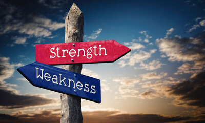 Strength and weakness - wooden signpost with two arrows, sunset sky in background © PX Media