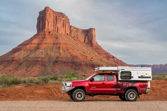 Moab, UT, USA - May 5, 2018: Toyota Tacoma truck with a pop up camper at Rocky Rapid parking on a shore of Colorado River with Castle Valley buttes in background.