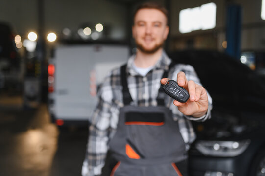Auto mechanic holding car key offering service