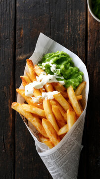 Crispy french fries with mushy peas and salsa on rustic wooden table