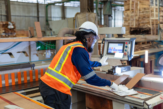 Operating woodworking controls, a carpenter handles plywood tasks with a pencil poised above a clipboard in the wood workshop.