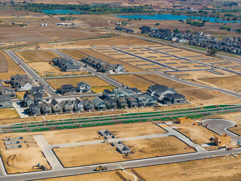 Aerial view of a new residential housing development under construction with suburban expansion, paved roads, and building foundations in Longmont, Colorado, United States.