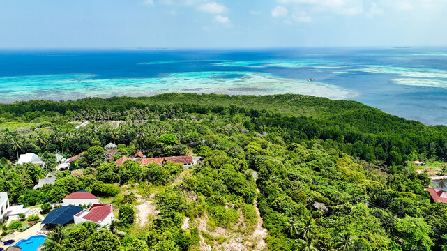 Aerial view of Karimunjawa featuring lush tropical vegetation, dense forests, coastal scenery, and turquoise waters of the Java Sea, Karimunjawa, Central Java, Indonesia.