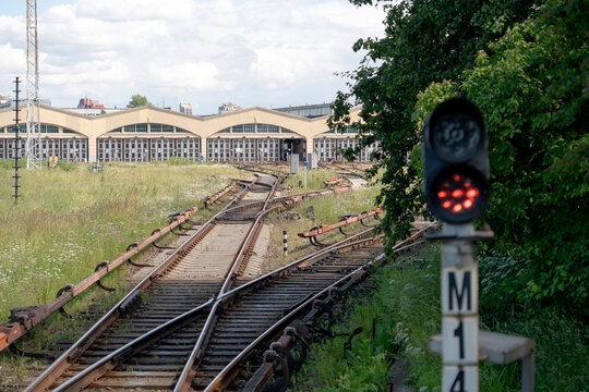 Rows of aging passenger carriages and dismantled train sections occupy an outdoor railway yard, with weathered paint, missing windows and industrial scrap.