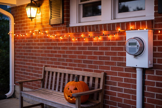 Smart electricity meter on brick wall with halloween lights, pumpkin
