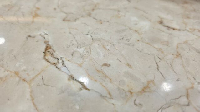 Cream marble surface with a small crack on the left side, showing natural stone veining, minor damage, texture, and architectural material detail.