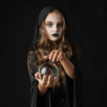 A young witch holding a clear crystal ball in hands