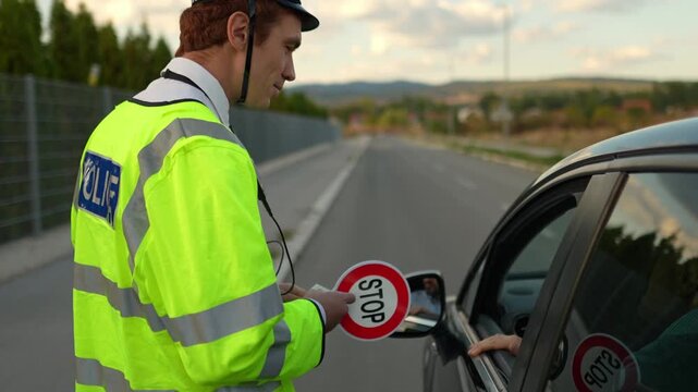 Police officer issuing a citation to a driver on an empty road in the late afternoon