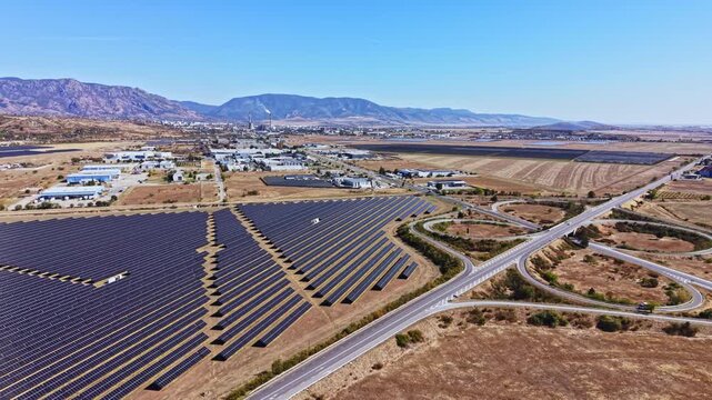 The solar energy farm shows rows of solar panels spread across the land with highways running through the area. Mountains are visible in the distance under a blue sky.