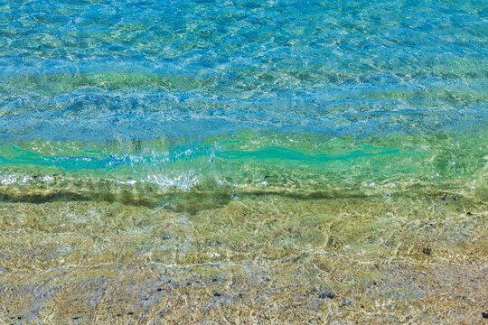 Close-up view of clear Atlantic Ocean waves washing over sand at Amadores beach, Gran Canaria. Spain.