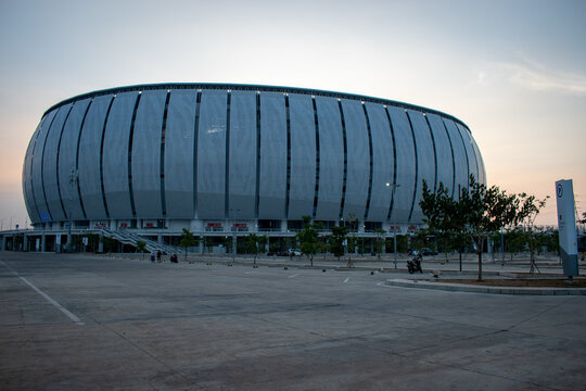 Jakarta, Indonesia - October 14, 2026: Jakarta International Stadium (JIS) photographed from the exterior at dusk, showing its oval facade, paved foreground, and evening sky.