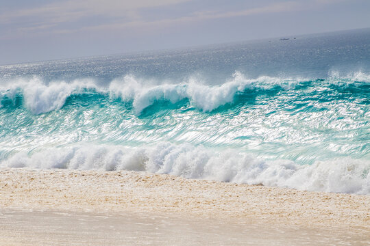 View of turquoise ocean waves crashing onto a sandy beach, Baja California Sur, Mexico.