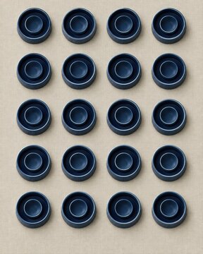 Bed bug interceptor cups in a navy satin glaze arranged on an oat linen surface, creating a clean pattern for pest control and home prevention