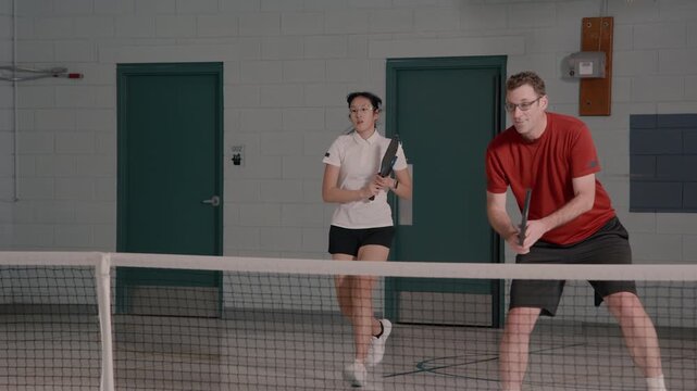 Co ed pickleball players in a modern gymnasium