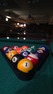 Billiard balls in triangle rack on green pool table in dimly lit billiard hall
