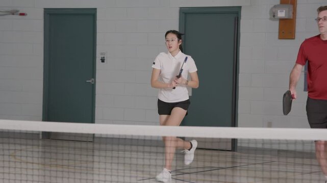 Co ed pickleball players in a modern gymnasium